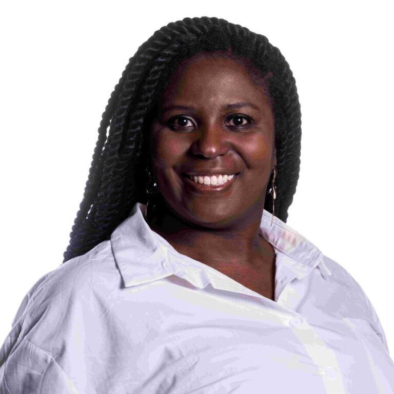 Woman with long braided hair wearing a white shirt, smiling and looking at the camera against a plain white background.